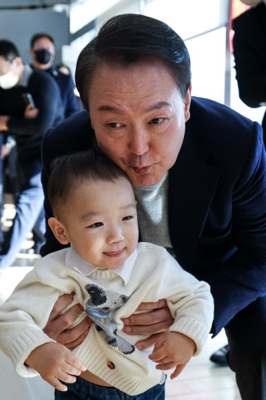 윤석열 대통령이 17일 서울 서초동 아크로비스타 사저를 찾아 주민들에게 감사 인사를 전한 뒤 한 어린이와 기념촬영을 하고 있다. 2022.12.17  대통령실 제공