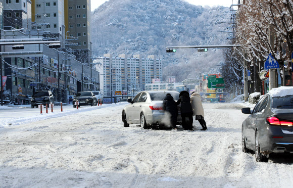 대설특보가 발령된 18일 오전 광주 남구 한 도로에서 시민들이 눈길을 빠져나가지 못하는 차량의 후미를 밀어주고 있다. 2022.12.18  연합뉴스