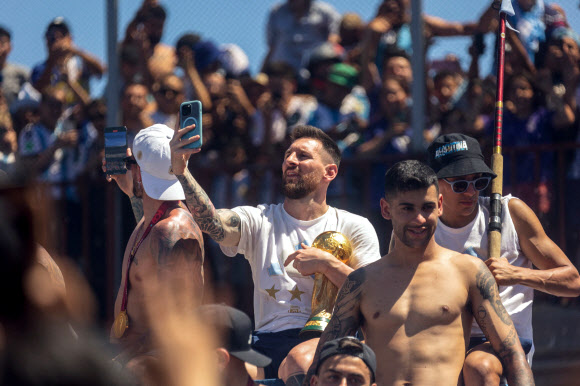 Argentine football star Lionel Messi (C) takes pictures with his phone while celebrating on board a bus with a sign reading “World Champions” with supporters after winning the Qatar 2022 World Cup tournament as they tour through Buenos Aires‘ downtown on December 20, 2022. - Millions of ecstatic fans are expected to cheer on their heroes as Argentina’s World Cup winners led by captain Lionel Messi began their open-top bus parade of the capital Buenos Aires on Tuesday following their sensational victory over France. AFP 연합뉴스