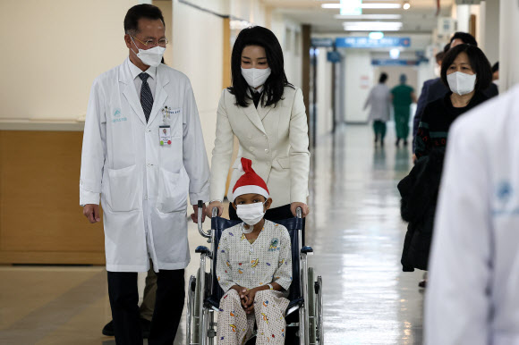 김건희 여사가 21일 서울 송파구 서울아산병원에서 심장질환 수술을 받고 회복 중인 캄보디아 아동 옥 로타군을 만나 의료진과 함께 이동하고 있다. 2022.12.21  대통령실 제공
