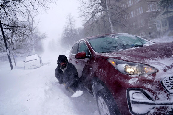 한 시민이 24일(현지시간) 미국 뉴욕주 버펄로에서 차를 움직이려 눈을 퍼내고 있다. AP