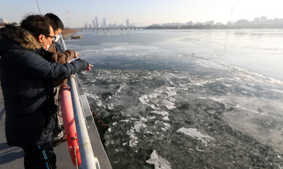 한파가 계속되며 올 겨울 들어 처음으로 한강 결빙이 관측된 25일 서울 시내 한강공원에서 시민들이 얼어붙은 한강을 바라보고 있다. 기상청은 25일 공식 관측 지점인 한강대교 교각 두 번째와 네 번째 사이 결빙이 관측됐다고 밝혔다. 올해 한강 결빙은 평년보다 16일 빠르게 관측됐다. 2022.12.25.뉴시스