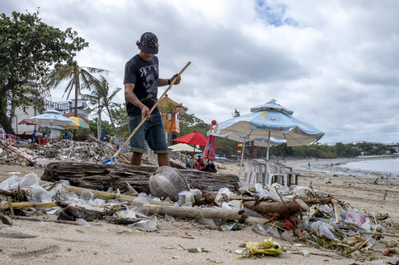 29일 인도네시아 발리 쿠타에서 한 남성이 잔해와 플라스틱 쓰레기를 청소하고 있다.2022.12.31 EPA연합뉴스