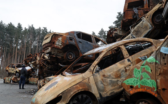8일(현지시간) 우크라이나 키이우 외곽도시인 이르핀에 파괴된 차량들이 쌓여 있다. 차량 겉면에 누군가 그린 해바라기들이 보인다. 2023.1.10  연합뉴스