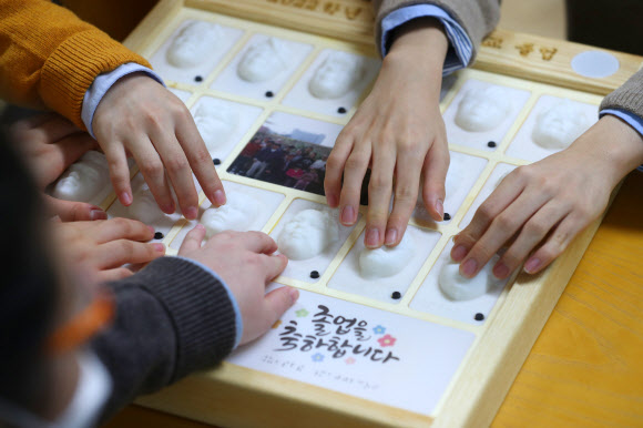 13일 대구시 남구 시각장애 학생을 위한 교육기관인 대구광명학교에서 열린 2022학년도 졸업식에서 졸업생들이 3D 프린터로 제작된 졸업앨범에서 친구 얼굴을 손끝으로 찾아보고 있다. 2023.1.13. 연합뉴스