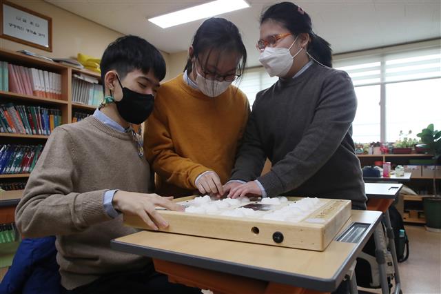 13일 오전 대구 남구 대명동 시각장애인 교육기관 대구광명학교에서 열린 2022학년도 졸업식에서 3D 프린터로 제작된 졸업앨범을 받은 졸업생들이 친구들의 얼굴을 손끝으로 만지며 목소리를 듣고 있다. 2023.1.13. 뉴스1