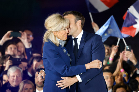 에마뉘엘 마크롱 프랑스 대통령과 영부인 브리지트 마크롱이 24일(현지시간) 파리의 상드마르스 광장에서 연임에 성공한 후 지지자들과 함께 기뻐하고 있다. AFP 연합뉴스