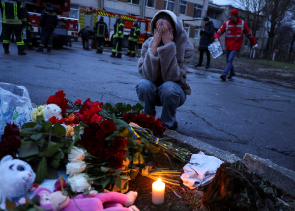 18일(현지시간) 우크라이나 키이우 외곽 브로바리에서 헬기 추락으로 14명이 사망하는 사고가 발생한 가운데 사고 현장 근처에서 한 여성이 사망자들을 추모하는 꽃을 내려놓은 뒤 흐느끼고 있다. 2023.1.18 로이터 연합뉴스