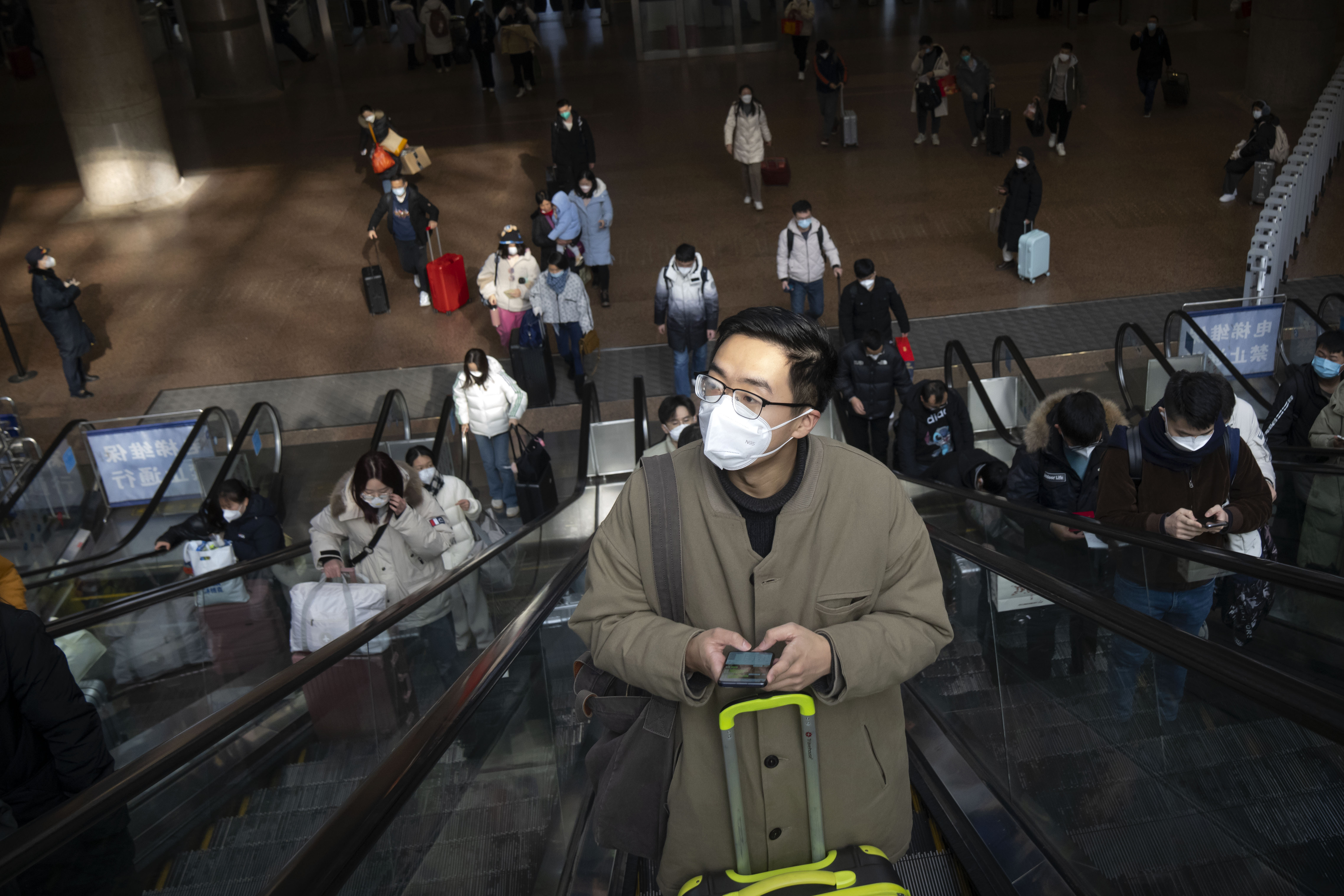 귀성길에 오른 한 베이징 시민이 18일(현지시간) 마스크를 쓰고 에스컬레이터를 타고 있다. 베이징 AP 연합뉴스