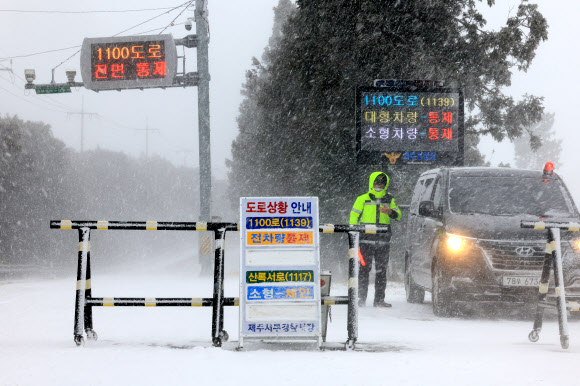 설 연휴 마지막 날이자 폭설이 시작된 24일 오전 제주시 해안동 축산진흥원 앞에서 경찰이 산간도로 출입을 통제하고 있다. 2023.1.24 연합뉴스