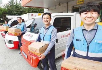 우정사업본부 직원들이 배송차량 앞에서 소포를 들고 활짝 웃고 있다. 우정사업본부 제공