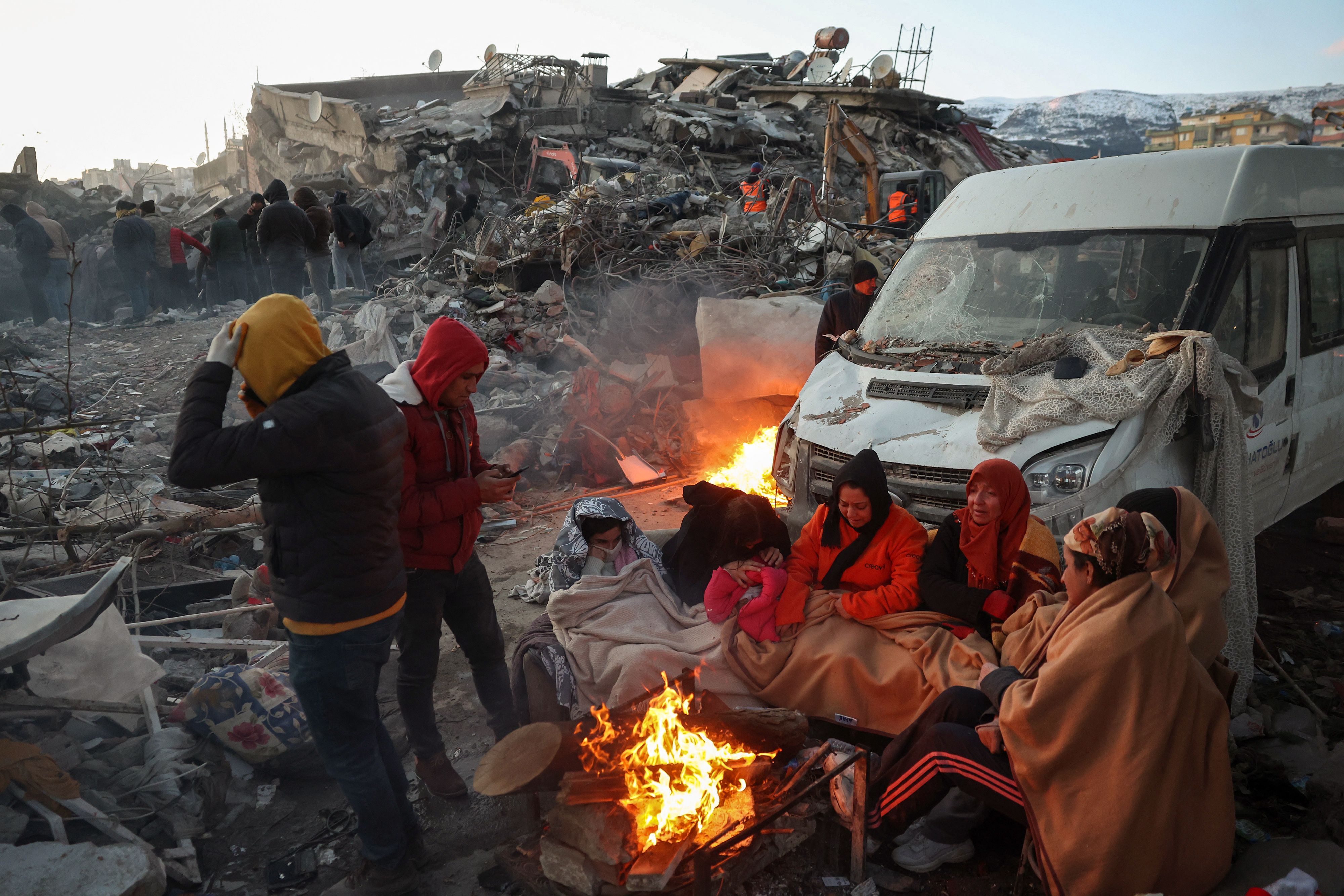 8일(현지시간) 튀르키예 남부 카라만라스의 무너진 건물 밖 모닥불 옆에 생존자들이 모여 있다. AFP 연합뉴스