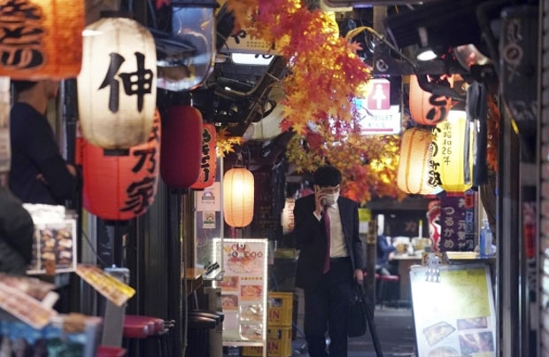 지난달 25일 일본 도쿄에서 마스크를 착용한 한 남성이 뒷골목 술집 거리를 따라 홀로 걸어가고 있다./사진=AP 연합뉴스