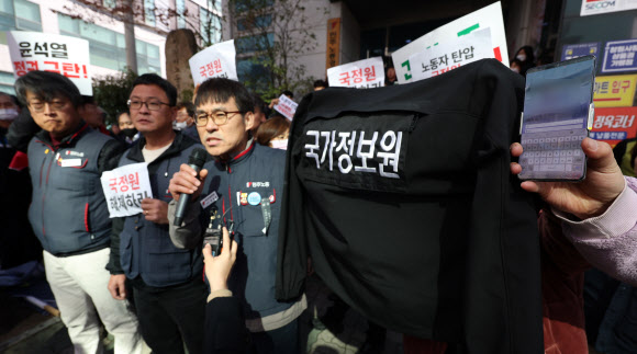 민주노총 경남지역본부 조합원이 23일 오전 경남 창원시 성산구 본부 입구에서 국정원 옷과 휴대폰 등을 보이고 있다. 이날 국정원 한 수사관이 기자회견이 진행되는 동안 촬영을 시도하다 민노총 조합원에 적발됐다. 2023.2.23. 연합뉴스