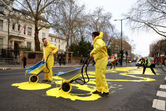 ‘당나귀들에 이끌리는’이란 시민단체 활동가들이 통행을 막은 채 노란색 페인트를 도로 위에 부으며 즐거워하고 있다. 런던 로이터 연합뉴스