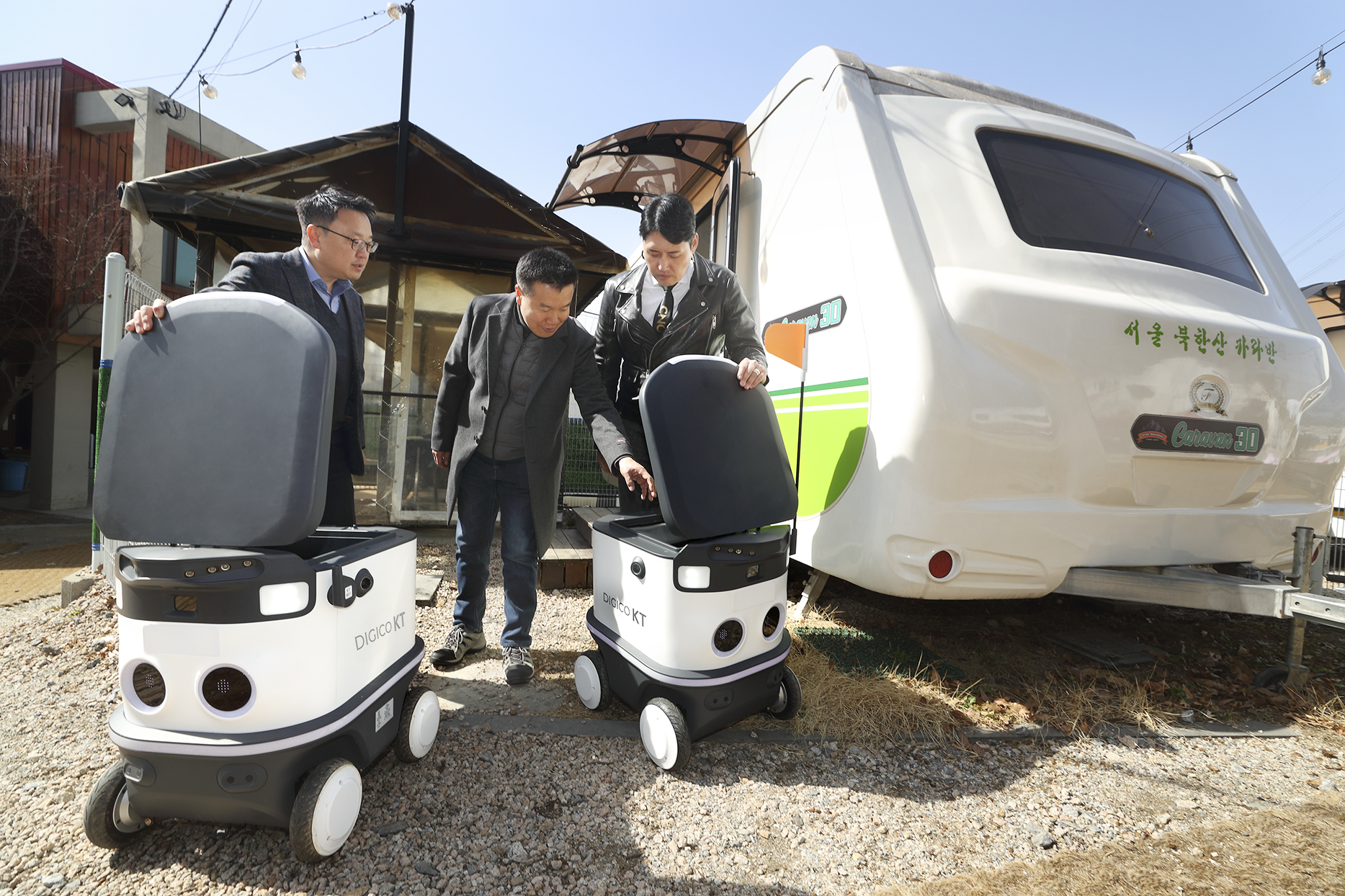 KT와 캠핑 관련 업체의 관계자들이 서울 북한산 캠핑장에서 서비스 출시 예정인 캠핑장 자율주행 배송 로봇을 들여다보고 있다. KT 제공