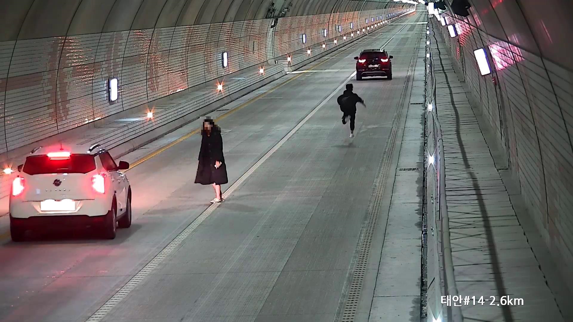 보령해저터널에서 승용차를 세워놓고 남성이 뜀박질을 하고 여성은 서성이고 있다.
