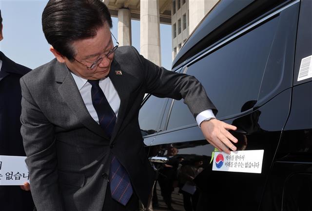 이재명 더불어민주당 대표가 22일 서울 여의도 국회에서 대일굴종외교 규탄 태극기달기 운동 행사의 일환으로 차량에 태극마크와 ‘역사를 팔아서 미래를 살 수는 없습니다’라고 적힌 스티커를 부착하고 있다. 2023.3.22. 공동취재