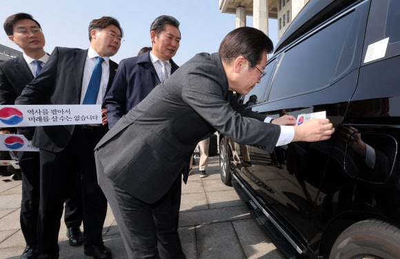 더불어민주당 이재명 대표가 22일 오전 서울 여의도 국회 본청 앞에서 열린 대일굴종외교 규탄 태극기달기 운동 행사에서 ‘역사를 팔아서 미래를 살 수는 없습니다’ 문구가 담긴 태극기 스티커를 차량에 부착하고 있다. 2023.3.22. 공동취재
