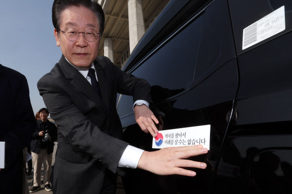 더불어민주당 이재명 대표가 22일 오전 서울 여의도 국회 본청 앞에서 열린 대일굴종외교 규탄 태극기달기 운동 행사에서 ‘역사를 팔아서 미래를 살 수는 없습니다’ 문구가 담긴 태극기 스티커를 차량에 부착하고 있다. 2023.3.22. 공동취재