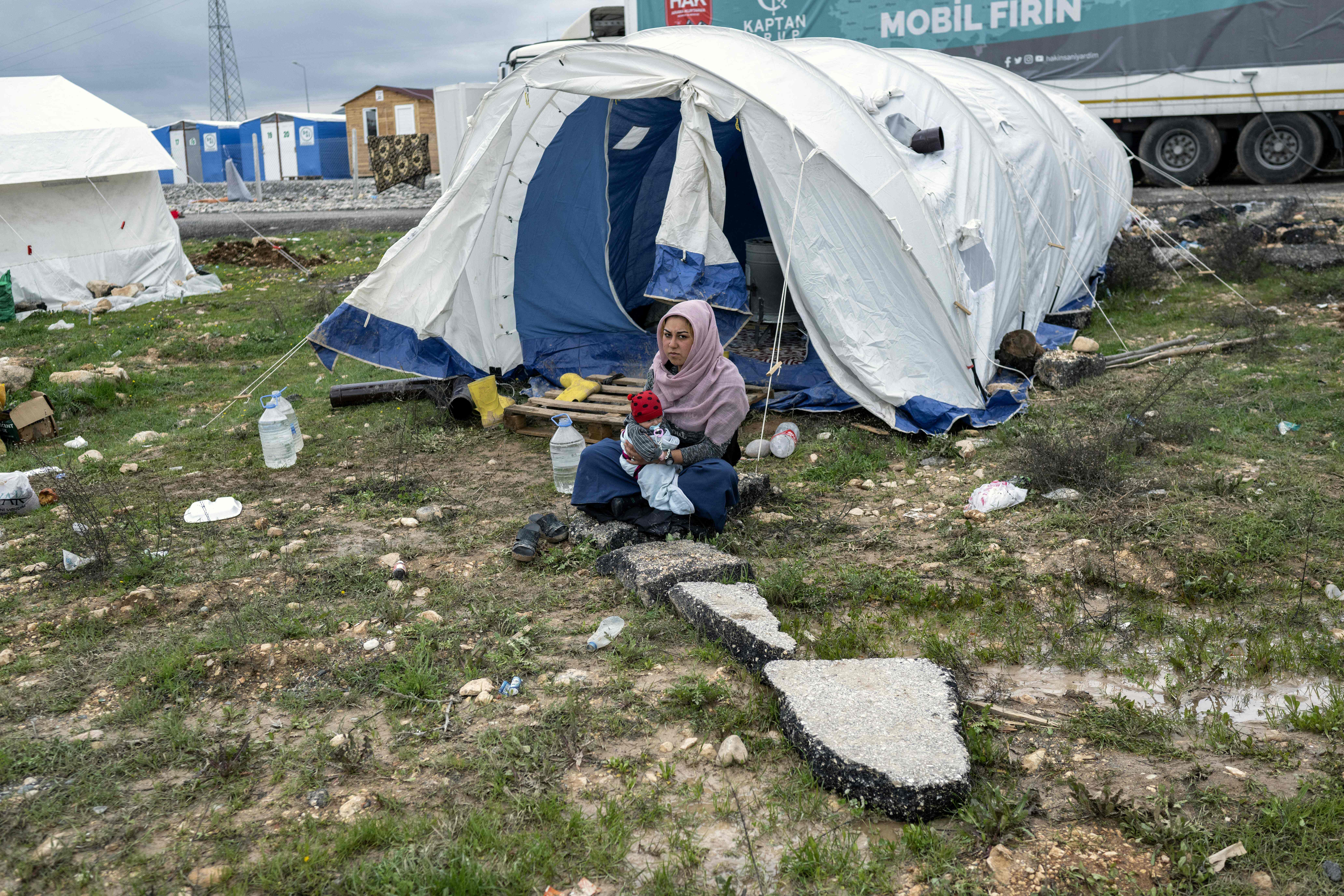 지진으로 초토화된 튀르키예 남동부 지역에 폭우가 내린 뒤인 지난 26일(현지시간) 아드야만의 이재민 텐트촌에 한 쿠르드족 여성이 신생아를 품에 안은 채 텐트 앞에 앉아 있다.  아드야만 AFP 연합뉴스