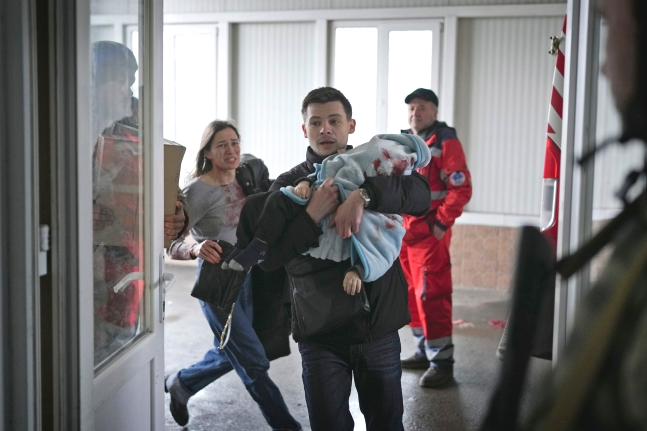4일(현지시간) 마리나 야츠코(왼쪽)와 남자친구 페도르가 러시아군 포격으로 다친 18개월 된 아들 키릴을 안고 우크라이나 마리우폴의 한 병원 응급실로 뛰어가고 있다. 2022.3.6 AP 연합뉴스