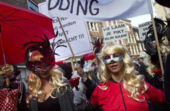 마스크로 얼굴을 가린 수백 명의 성매매업소 종사자들과 이들을 지지하는 사람들이 암스테르담 시내 홍등가에서 호객용 유리 진열시설 철거에 반대하는 시위를 하고 있다. AP/뉴시스