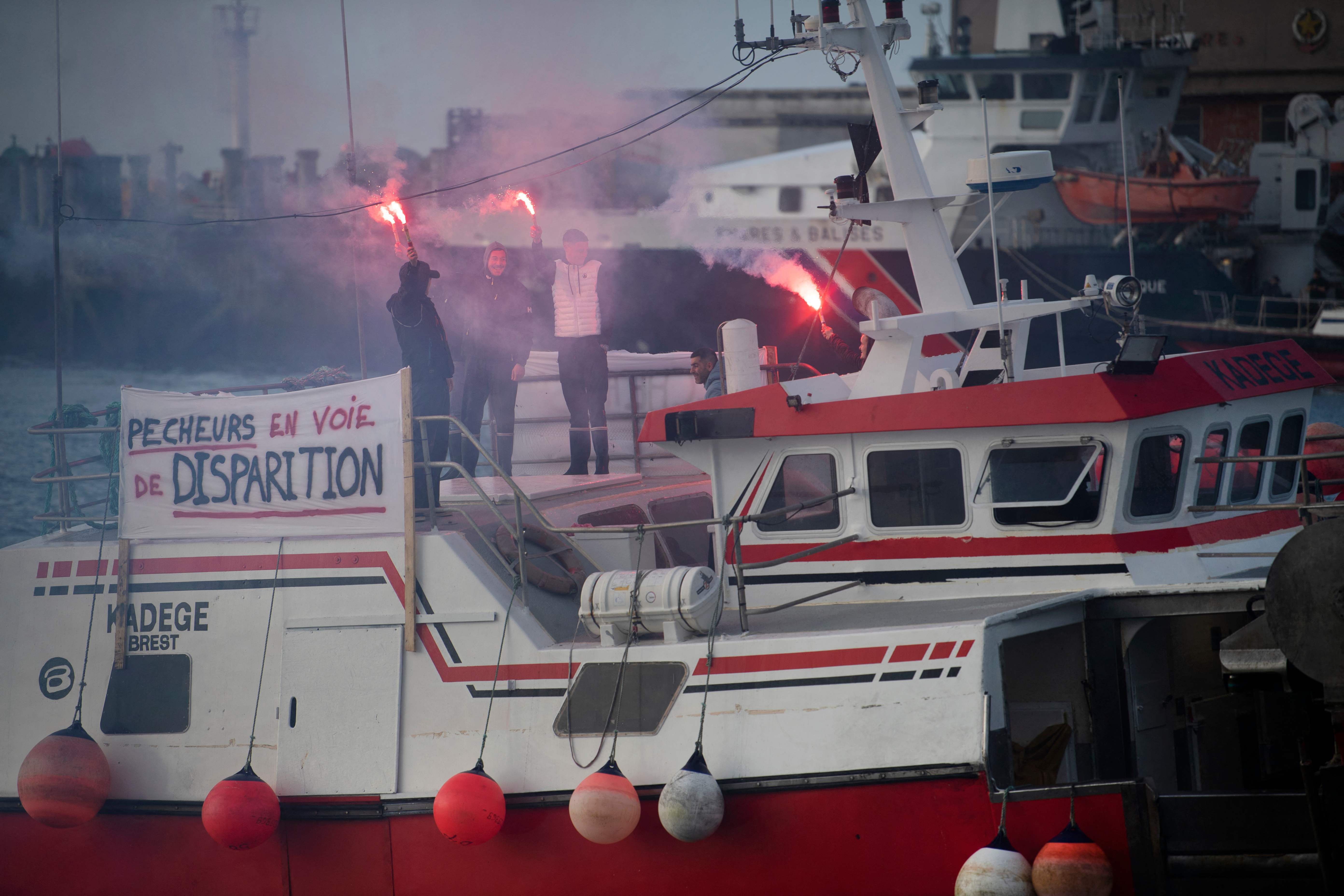 30일(현지시간) 프랑스 서부 브레스트항의 선박에서 어부들이 섬광탄을 흔들며 항의하고 있다. 현수막에는 “어민은 멸종 위기종입니다”라고 적혀 있다. 브레스트 AFP 연합뉴스