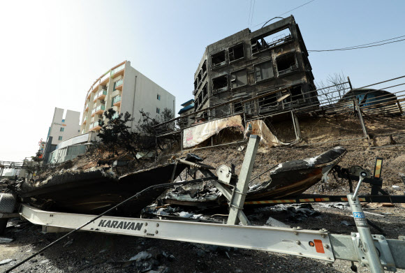 12일 강원도 강릉시 사근진 해변 인근 펜션 밀집 지역 건물 앞에 전날 발생한 산불로 타버린 보트가 세워져 있다. 전날 순간풍속 초속 30m에 달하는 강풍 탓에 확산한 산불로 산림 379㏊가 소실되고 주택과 펜션 등 시설물들이 피해를 봤다. 2023.4.12 연합뉴스