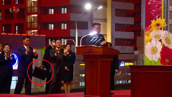 지난 16일 북한 김정은 국무위원장이 참석한 가운데 열린 평양 화성지구 1단계 1만 세대 살림집(주택) 준공식장에서 한 경호원이 검은 가방을 들고 김 위원장을 경호하고 있다. [조선중앙TV 화면] 2023.4.19 연합뉴스