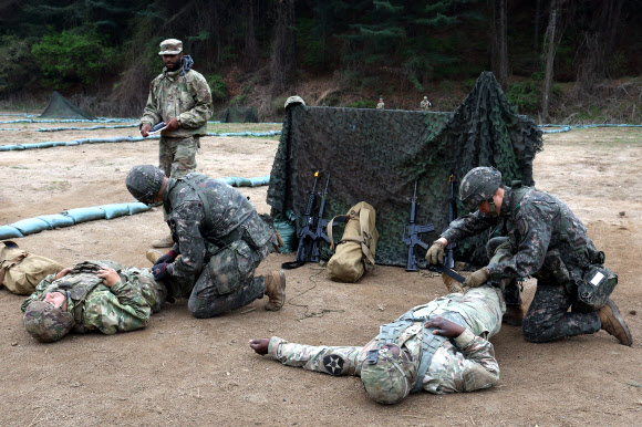 20일 경기도 포천시 로드리게즈 사격장에서 실시된 미2사단/한미연합사단 전문병사 휘장 시험 사전연습에서 한국군 장병이 미군 장병을 치료하는 훈련을 하고 있다. 미2사단은 이달 28일까지 전문보병휘장, 전문야전의무병휘장, 전문병사휘장 시험을 진행한다. 2023.4.20. 연합뉴스