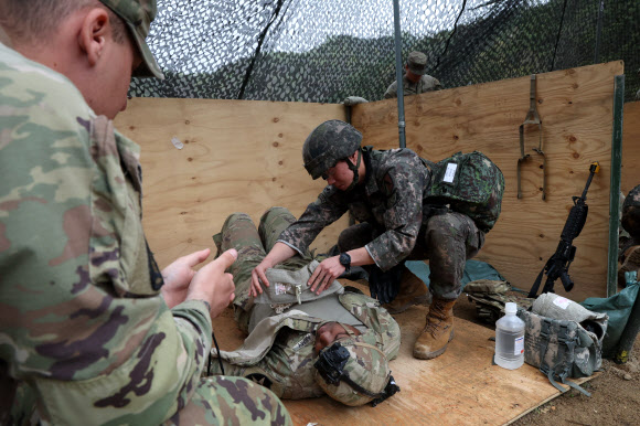 20일 경기도 포천시 로드리게즈 사격장에서 실시된 미2사단/한미연합사단 전문병사 휘장 시험 사전연습에서 한국군 장병이 미군 장병을 치료하는 훈련을 하고 있다. 미2사단은 이달 28일까지 전문보병휘장, 전문야전의무병휘장, 전문병사휘장 시험을 진행한다. 2023.4.20 연합뉴스