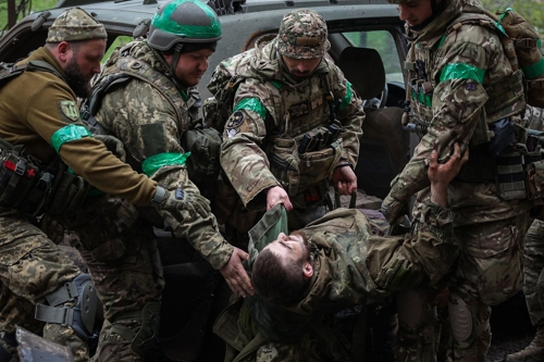 우크라이나 병사들이 23일 치열한 참호전이 벌어지고 있는 도네츠크 지역 바흐무트에서 부상병을 옮기고 있다. 바흐무트 AFP 연합뉴스