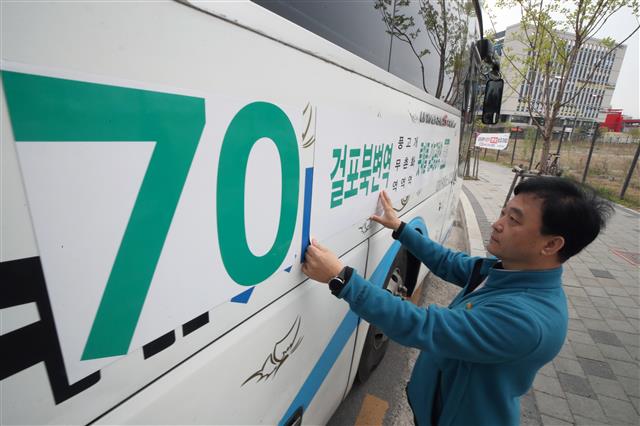 경기 김포시는 골드라인 혼잡도 완화를 위해 24일 오전 7시5분부터 한 시간 동안 걸포북변역에서 김포공항역까지 가는 70번 버스 8회(편도)를 추가 투입했다.  김포시 관계자가 새로 투입된 전세버스에 안내 홍보물을 붙이고 있다. 2023.4.24. 뉴스1