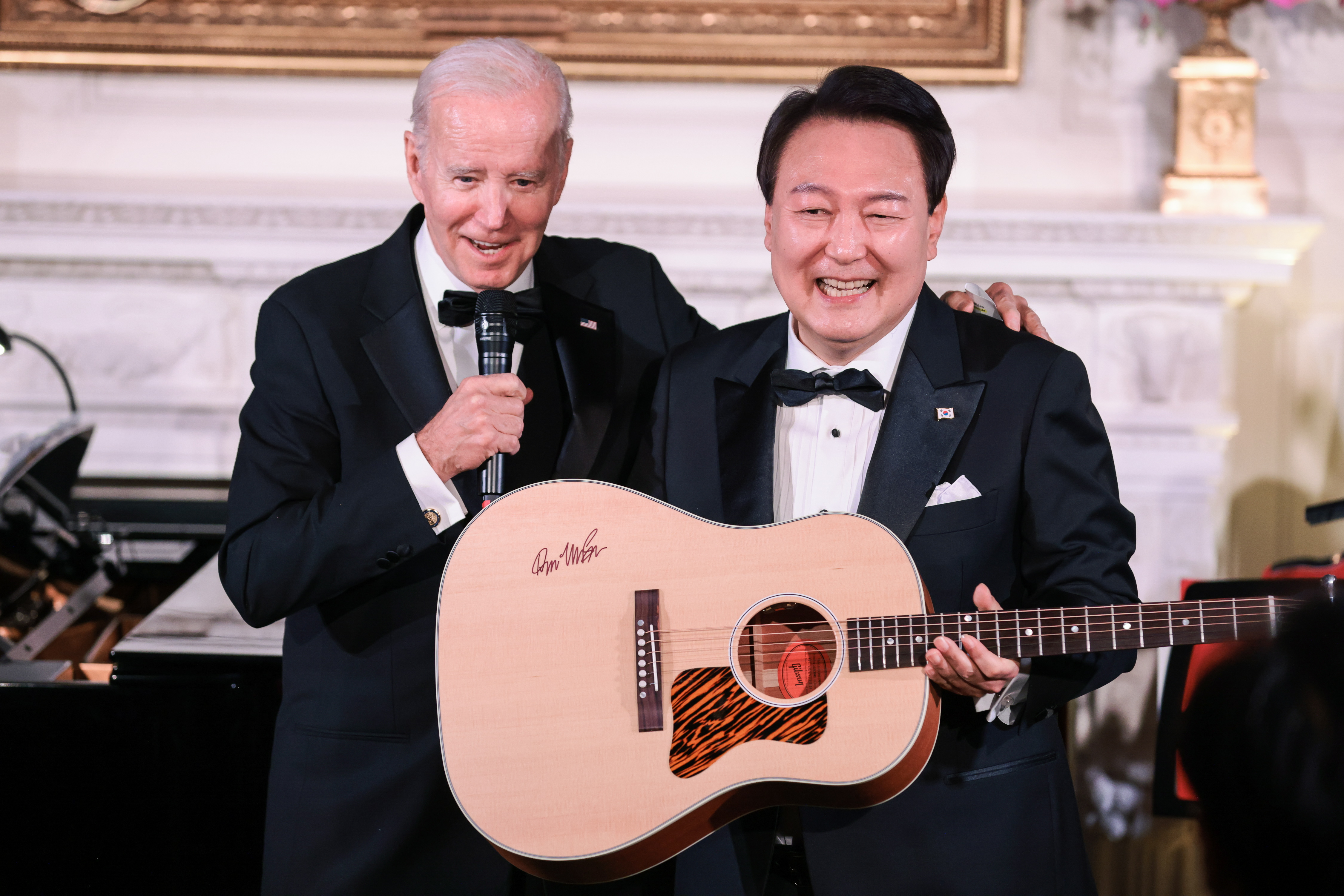 2023년 4월 26일 미국 워싱턴 백악관 이스트룸에서 열린 국빈만찬에서 조 바이든 미국 대통령이 지켜보는 가운데 한국의 윤석열(R) 대통령이 돈 맥클린이 사인한 어쿠스틱 기타를 들고 있다. EPA/올리버 콘트레라스/풀