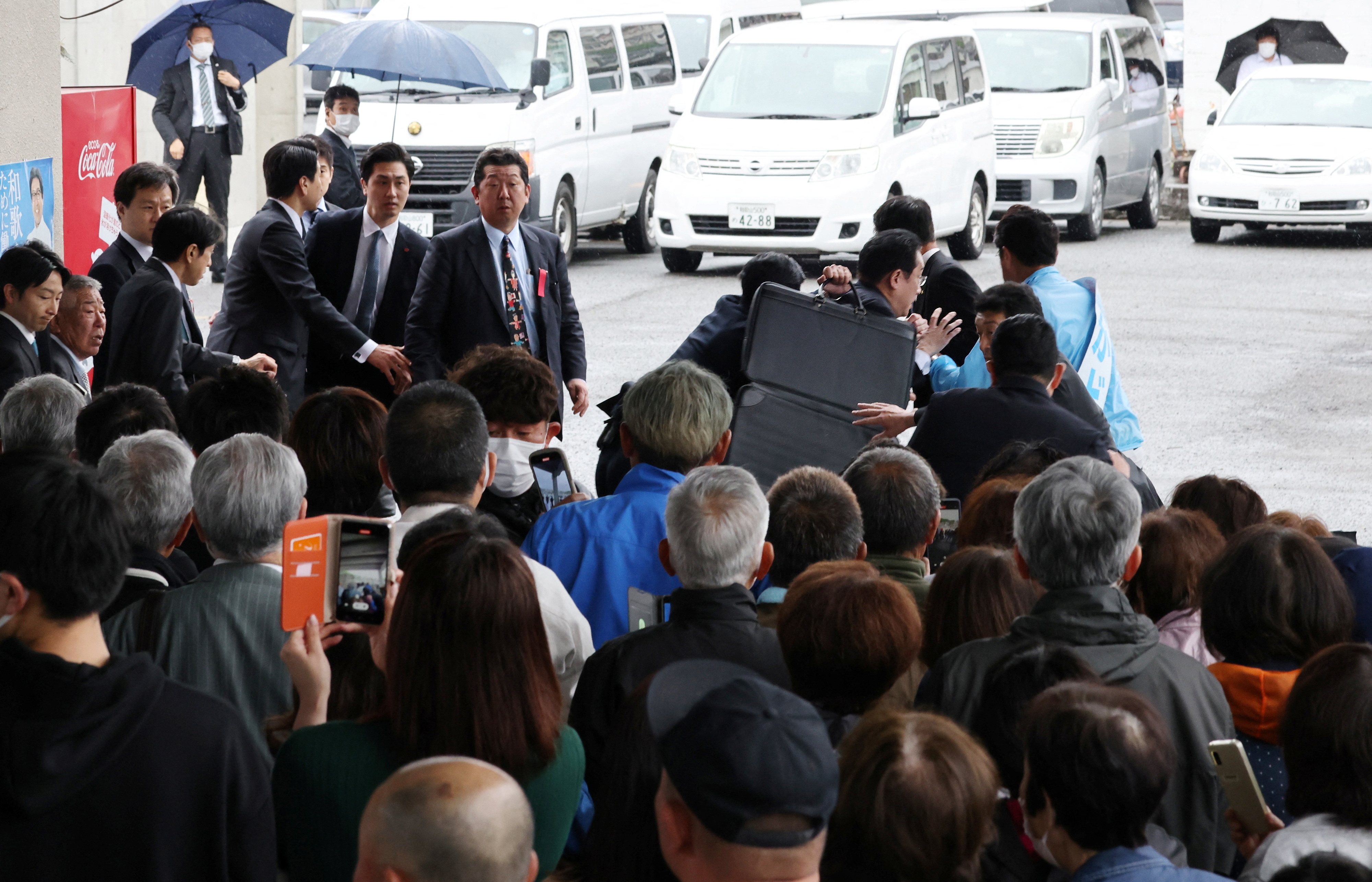 기시다 후미오 일본 총리가 15일 오전 11시 30분쯤 와카야마현 사이카자키 어시장에서 중의원 보궐 선거 지원 유세 직전 1m 앞에 폭발물이 떨어지자 방탄 가방을 펼친 경호원들의 경호를 받으며 피신하고 있다. 와카야마 로이터 연합뉴스