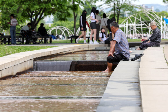 전국 대부분 지역 낮 기온이 25도 내외로 오른 2일 오후 서울 여의도한강공원을 찾은 시민들이 물길에 발을 담그고 있다. 2023.5.2 연합뉴스