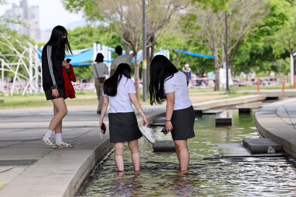 전국 대부분 지역 낮 기온이 25도 내외로 오른 2일 오후 서울 여의도한강공원을 찾은 학생들이 물길에 발을 담그고 있다. 2023.5.2 연합뉴스