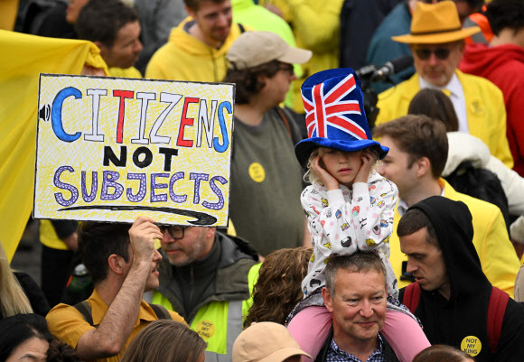영국 국왕 찰스 3세의 대관식이 열리는 6일(현지시간) 런던 트래펄가 광장에서 군주제를 반대하는 시위대가 모인 가운데 한 시민이 ‘시민은 신하다 아니다’라고 쓰인 손팻말을 들고 있다. 2023.5.6 AFP 연합뉴스