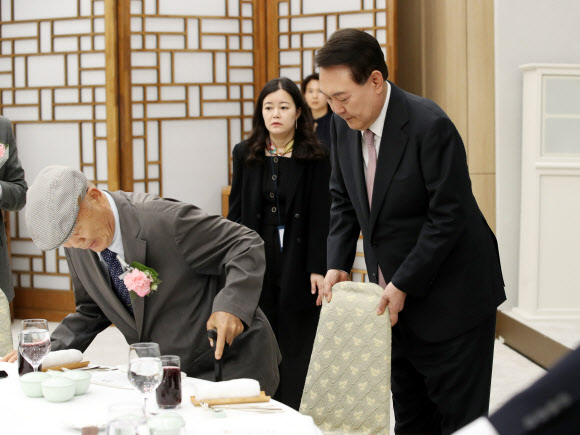 윤석열 대통령이 15일 서울 용산 대통령실 청사에서 열린 제42회 스승의 날 기념 현장교원 초청 오찬 간담회에서 충암고 시절 은사인 최윤복 선생님의 착석을 돕고 있다. 2023.5.15. 대통령실통신사진기자단