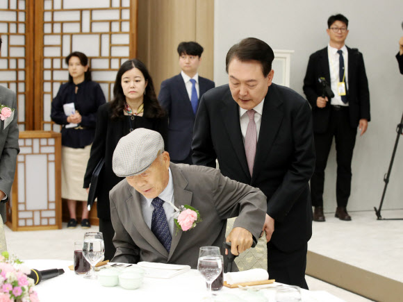 윤석열 대통령이 15일 서울 용산 대통령실 청사에서 열린 제42회 스승의 날 기념 현장교원 초청 오찬 간담회에서 충암고 시절 은사인 최윤복 선생님의 착석을 돕고 있다. 2023.5.15. 대통령실통신사진기자단