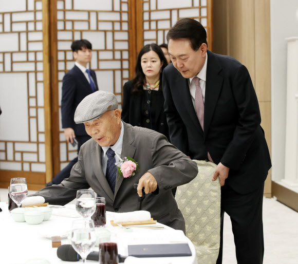 윤석열 대통령이 15일 서울 용산 대통령실 청사에서 열린 제42회 스승의 날 기념 현장교원 초청 오찬 간담회에서 충암고 시절 은사인 최윤복 선생님의 착석을 돕고 있다. 2023.5.15. 대통령실통신사진기자단