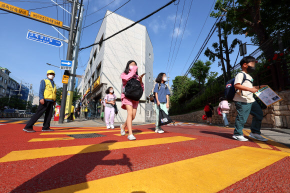 어린이들이 17일 오전 서울 구로구 덕의초등학교에서 노란색 횡단보도를 건너 등교하고 있다.  노란색 횡단보도는 운전자가 횡단보도의 색깔만으로도 어린이 보호구역임을 명확하게 인식할 수 있도록 노랗게 칠한 횡단보도로, 전국 12개 어린이 보호구역에서 3개월간 시범 운영 중이다. 2023.5.17 연합뉴스