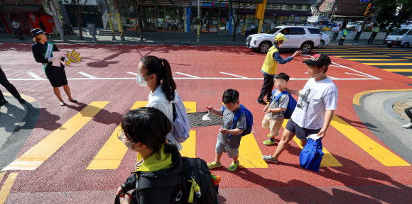 어린이들이 17일 오전 서울 구로구 덕의초등학교에서 노란색 횡단보도를 건너 등교하고 있다.  노란색 횡단보도는 운전자가 횡단보도의 색깔만으로도 어린이 보호구역임을 명확하게 인식할 수 있도록 노랗게 칠한 횡단보도로, 전국 12개 어린이 보호구역에서 3개월간 시범 운영 중이다. 2023.5.17 연합뉴스