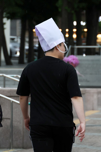비가 내린 18일 오후 우산을 미리 챙기지 못한 시민이 쇼핑백으로 비를 가린 채 서울역 인근 거리를 지나고 있다. 2023.5.18 연합뉴스