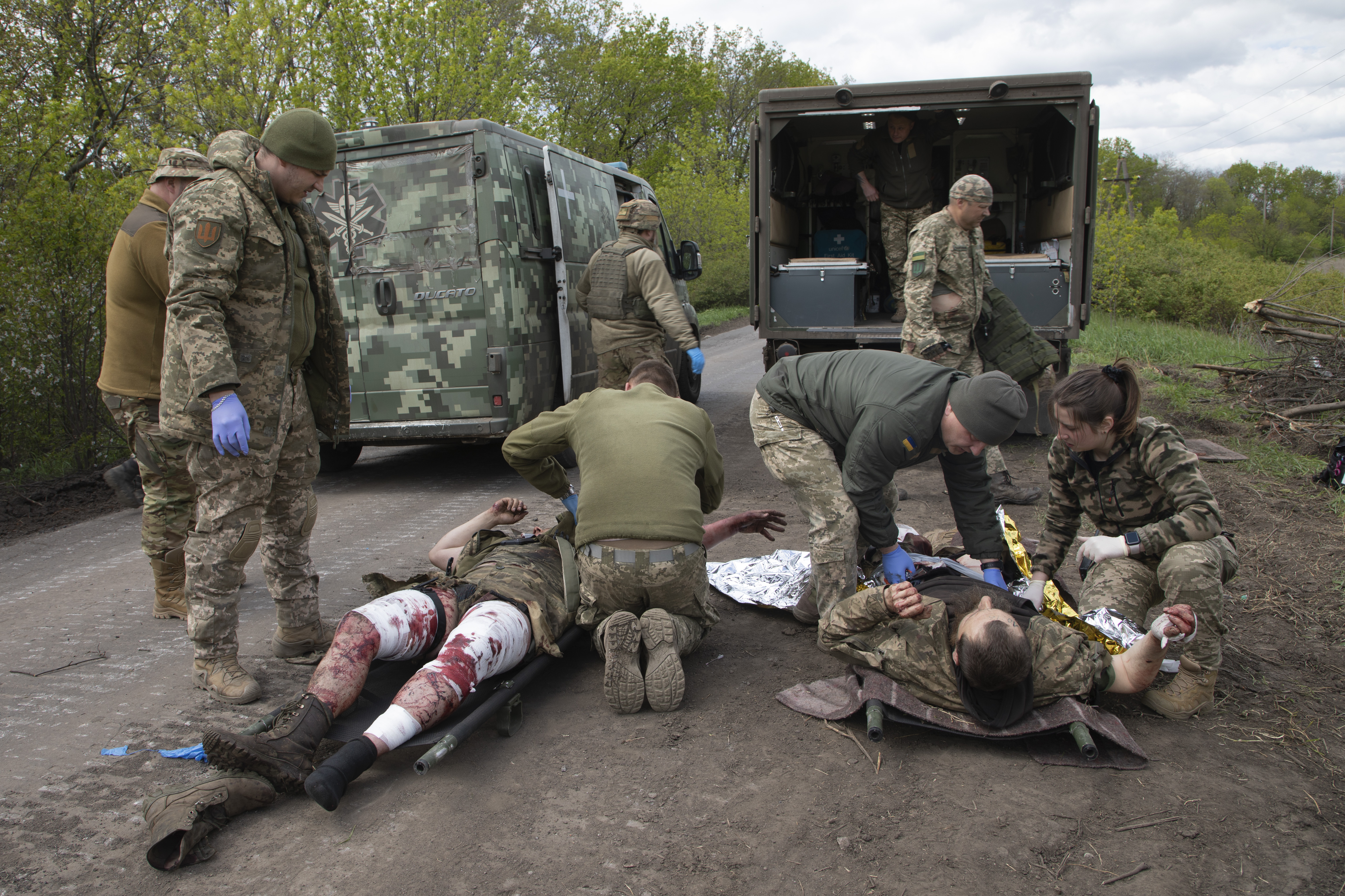 11일(현지시간) 우크라이나 바흐무트 인근 도로에서 우크라이나 군의관들이 다친 병사들에게 응급처치를 하고 있다. 2023.5.11 AP 연합뉴스