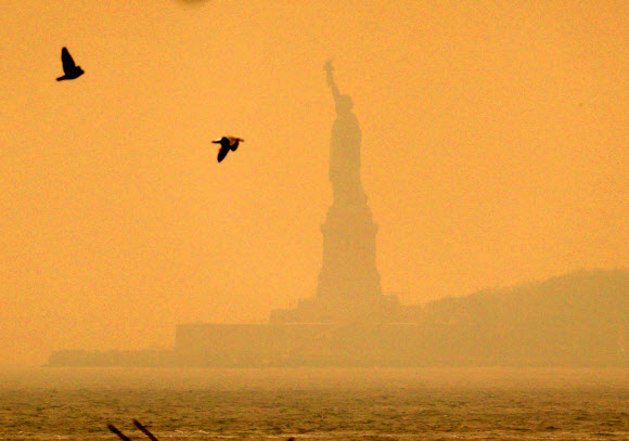 7일(현지시간) 캐나다 산불의 영향으로 미국 뉴욕의 하늘이 오렌지색으로 변한 가운데 자유의 여신상이 연기에 휩싸여 뿌옇게 보이고 있다. 2023.6.7 UPI 연합뉴스