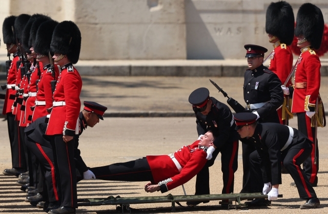 10일(현지시간) 영국 근위병이 찰스 3세 국왕의 공식 생일을 기념하는 ‘군기분열식’ 최종 리허설을 하다 실신해 쓰러져 있다. AFP 연합뉴스