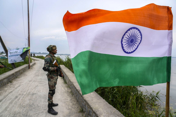 세계 환경의 날인 5일(현지시간) 인도령 카슈미르 스리나가르에서 인도 군인들이 오염된 호수의 잡초를 제거하는 동안 한 병사가 국기 근처에서 경비를 서고 있다. 사진은 기사 내용과 무관함. 2023.6.5 AP 연합뉴스