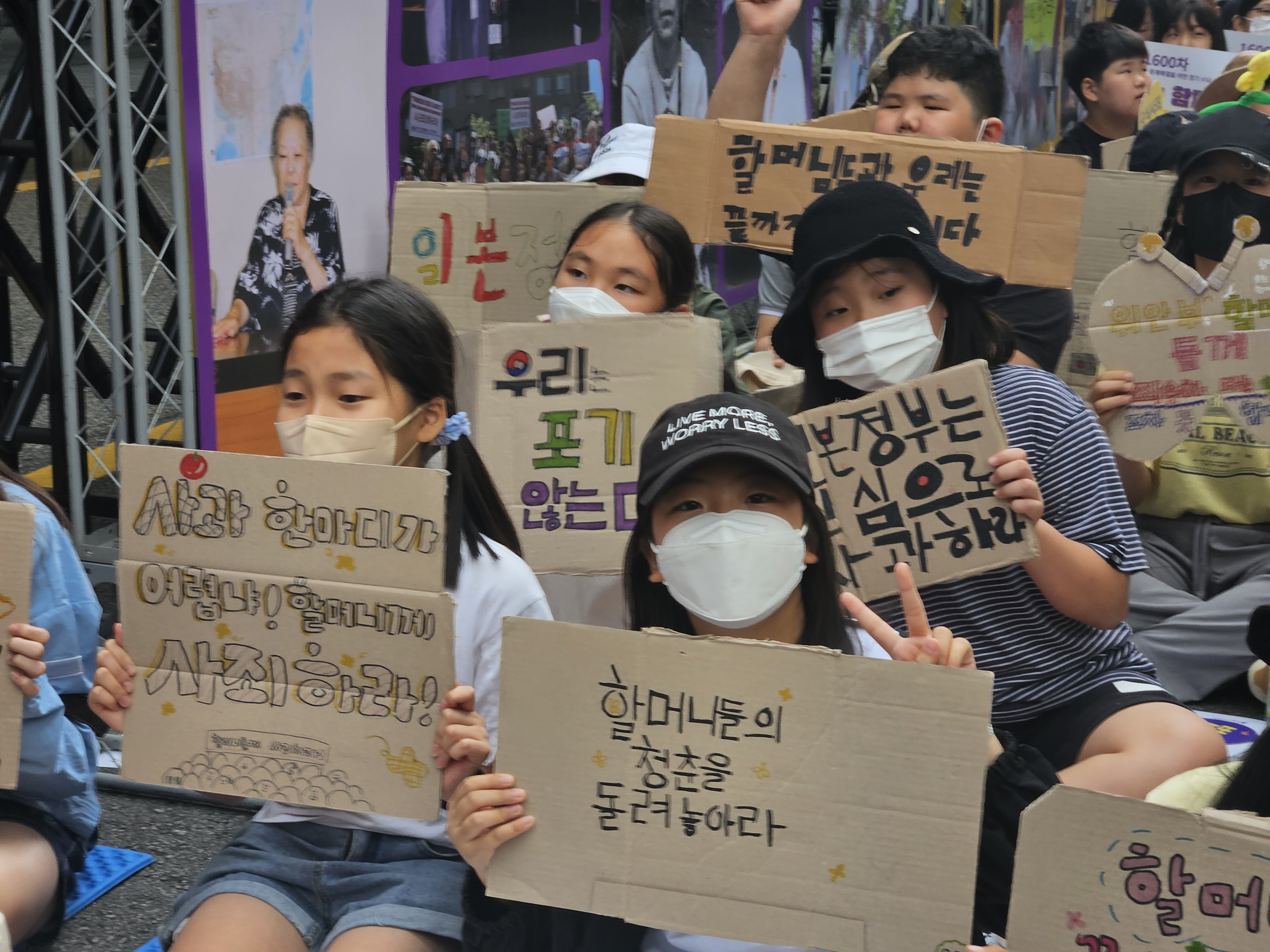 14일 낮 12시 서울 종로구에서 열린 ‘1600차 일본군 성노예제 문제해결을 위한 수요시위’에 참석한 학생들이 손팻말을 들어보이고 있다. 손지연 기자